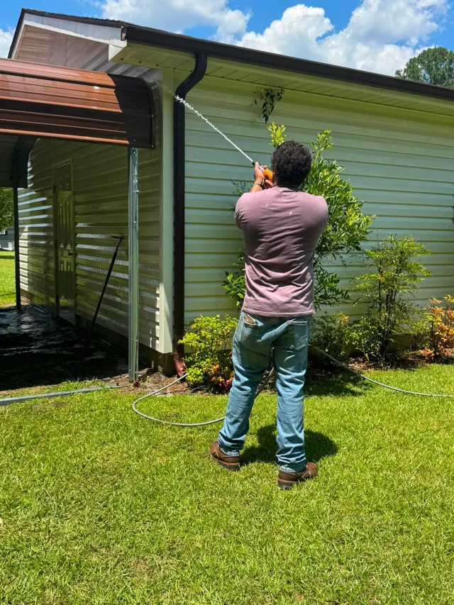Technician soft washing cream vinyl siding on a Jacksonville NC home